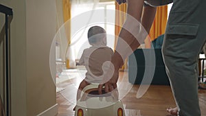 baby rides a motor scooter indoors. dad rides his son teaches him to ride a scooter around the room at home. happy