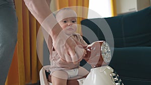 Baby rides a motor scooter indoors. Dad rides his son teaches him to ride a scooter around the room at home. Happy