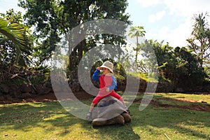 Baby riding giant turtle