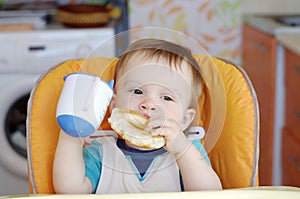 Baby with round cracknel and cup of tea photo