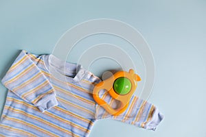 Baby`s accessories. Shirt for newborn and rattle on blue background. Infancy concept.