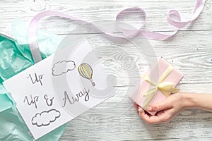 Baby`s bootees and gift box on wooden background