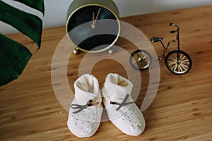 Baby`s boots and toys on wooden background. Waiting for baby. white shoes for newborn on the table