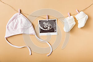 baby s cap ultrasound picture pair woolen shoes hanging clothesline against orange backdrop. High quality photo