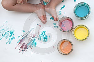 BabyÃ¢â¬â¢s feet and homemade colorful paints in glass jars. Dough and food colorants on a white background. Handmade and art with ki photo