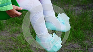 Baby`s feet in turquoise shoes with bows