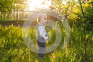 Baby`s first independent steps in the garden in sunlight. Cute summer blond girl laughing in the garden.