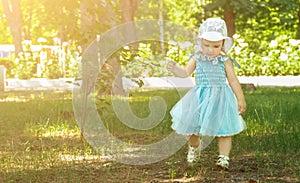 Baby`s first steps. cute caucasian one year old child girl walking in the park in summer