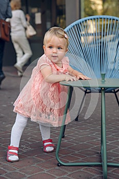 Baby`s first steps.The first independent steps. Baby girl walking in the park with chair support