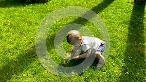 Baby's first steps on a green lawn. Baby trying to go crawling on the grass