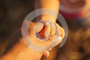 Baby`s hand hold his father`s hand in sunset time