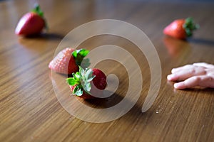 Baby s hand manipulating different fruits on a wooden table