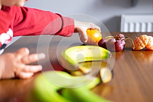 Baby s hand manipulating different fruits on a wooden table