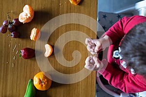 Baby s hand manipulating different fruits on a wooden table