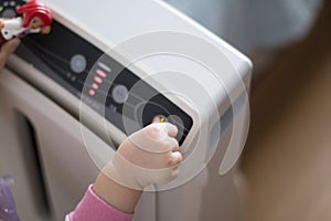 The baby`s hand pressing the power button on the air purifier to clean up the polluted air