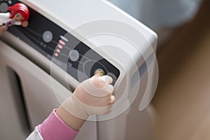 The baby`s hand pressing the power button on the air purifier to clean up the polluted air