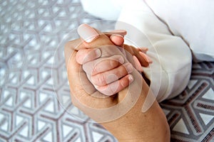 Baby`s hand squeezes mom`s thumb