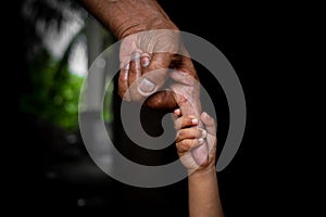 A baby`s hands holding tightly A senior man`s old age finger. Family, Generation, Support and people concept.