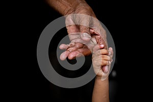 A baby`s hands holding tightly A senior man`s old age finger. Family, Generation, Support and people concept.