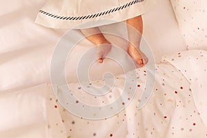 Baby`s legs on the bed. little baby legs in dress. top view