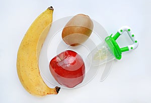 Baby`s nibbler and fresh ripe fruits apple, banana and kiwi on white background photo