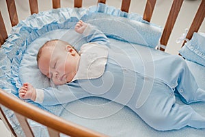 Baby`s restful sleep. Newborn baby in a wooden crib. The baby sleeps in the bedside cradle.