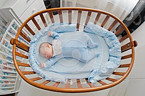Baby`s restful sleep. Newborn baby in a wooden crib. The baby sleeps in the bedside cradle.