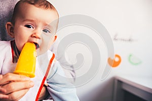 Baby savoring an orange ice cream