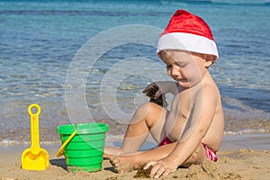 Baby by the sea in a cap of Santa Claus