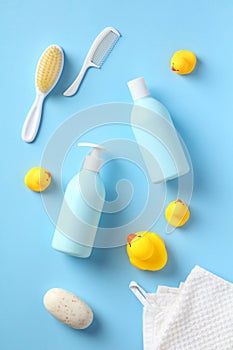 Baby shampoo and body wash with bathing accessories on blue background. Flat lay, top view shampoo bottle, shower gel, yellow