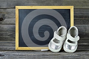 Baby shoes and blank blackboard