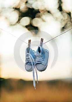 Baby shoes clipped on a string with autumn blurry background