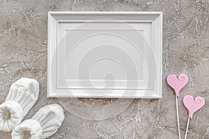 Baby shoes and frame for baby shower design on gray background top view mock-up