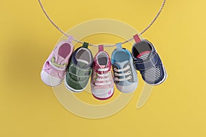 Baby shoes hanging on the clothesline on yellow