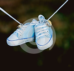 Baby shoes hanging by the shoe laces with the rings