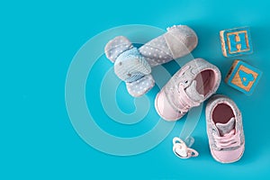 Baby shoes, pacifier and toys on blue background