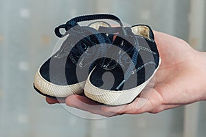 Baby shoes on parental hand