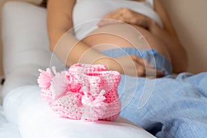 Baby shoes pregnancy woman. Beautiful pregnant woman holding pink baby shoes. Concept of pregnancy, maternity