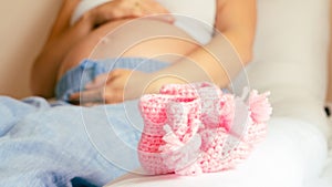 Baby shoes pregnancy woman. Beautiful pregnant woman holding pink baby shoes. Concept of pregnancy, maternity