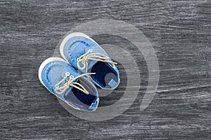 Baby shoes on a wooden background with space for text. Top view