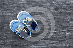 Baby shoes on a wooden background with space for text. Top view