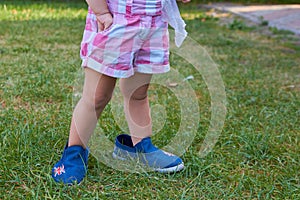 Baby in shorts,standing baby in shorts in big shoes on the grass