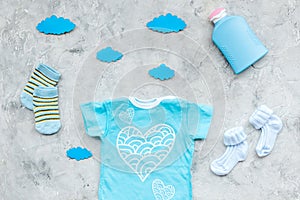 Baby shower concept. Baby`s clothes and accessories on grey background top view