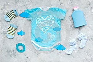 Baby shower concept. Baby`s clothes and accessories on grey background top view