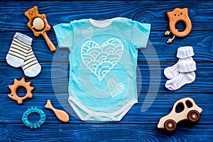Baby shower concept. Baby`s clothes and toys on blue wooden background top view. Clothes for boy
