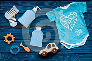 Baby shower concept. Baby`s clothes and toys on blue wooden background top view. Clothes for boy
