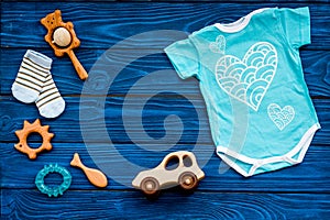 Baby shower concept. Baby`s clothes and toys on blue wooden background top view. Clothes for boy copy space