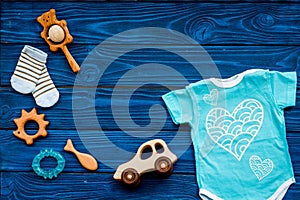 Baby shower concept. Baby`s clothes and toys on blue wooden background top view. Clothes for boy copy space