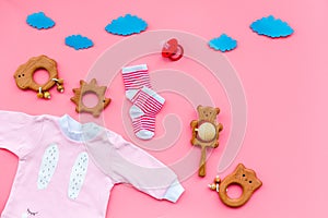 Baby shower concept. Baby`s clothes and toys on pink background top view copy space