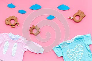 Baby shower concept. Baby`s clothes and toys on pink background top view copy space